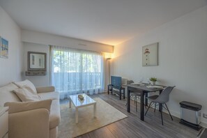 A modern living room with a sofa, coffee table, dining table, and chairs. - Studio des Ouvres - Welkeys (Deauville)