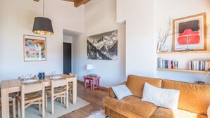 Un soggiorno con tavolo da pranzo in legno, divano e un quadro appeso.