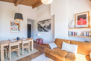 Una sala de estar con una mesa de comedor de madera, un sofá y un cuadro colgado.