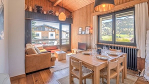 Un interno in legno con un tavolo da pranzo, sedie, un divano e una televisione.