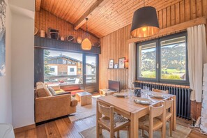 Un interior de madera con una mesa de comedor, sillas, un sofá y una televisión.