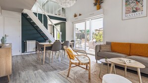 Un soggiorno moderno con una scala, un'area pranzo e un divano con un cuscino decorativo.