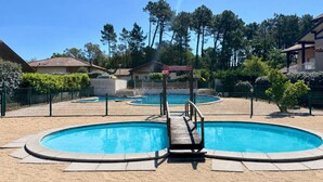 Una piscina con banchina in legno e posto di salvataggio, circondata da una recinzione e alberi.