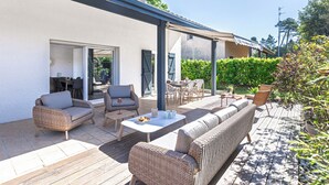 Patio esterno con mobili in vimini, un tavolo e una zona salotto coperta.