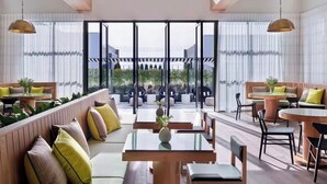 A modern interior with seating areas, tables, and large windows offering views of greenery. - Modern Luxury 1BR Skyline Views + Pool (Atlanta)