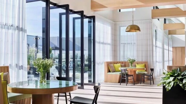 A modern interior with a round glass table, a sofa with cushions, and a hanging pendant light. - Modern Luxury 1BR Skyline Views + Pool (Atlanta)