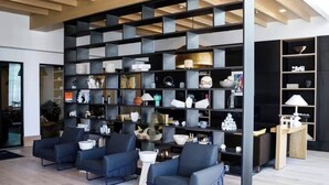 A modern interior with a large black shelving unit filled with various decorative items, a seating area with dark blue chairs, and a wooden ceiling. - Modern Luxury 1BR Skyline Views + Pool (Atlanta)