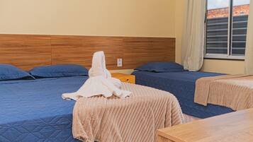 Quarto de hotel com duas camas, uma cabeceira de madeira, uma janela com cortinas e uma mesa de cabeceira de madeira.