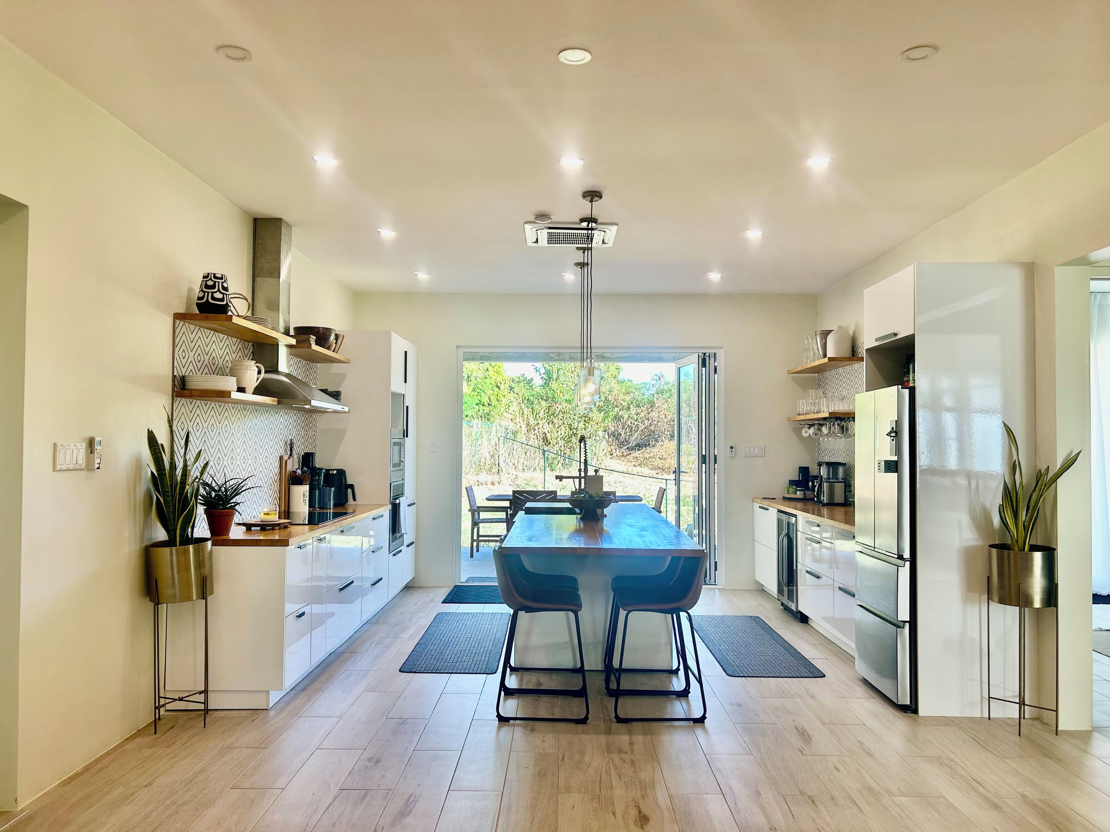 Een moderne keuken met een centraal eiland, ingebouwde apparatuur en uitzicht op buiten.