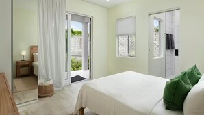 Ein Schlafzimmer mit Bett, Fenster, Tür und Blick nach draußen.