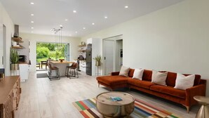 Ein modernes Wohnzimmer mit einer Couch, einem Couchtisch und einem Essbereich mit Stühlen.