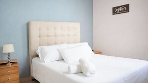 A neatly made bed with white linens and pillows, a wooden nightstand with a lamp, and a sign on the wall that reads 'together is my favorite place to be.' - 302-3 habitacion con baño privado en Coliving con terraza (Medellín)