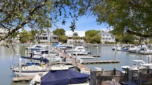 Un puerto deportivo con barcos amarrados, un edificio blanco con techo abovedado y una valla de madera.