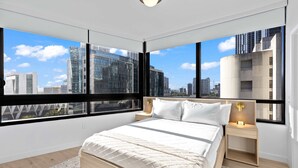 A modern bedroom with a large bed, a nightstand, a wall-mounted lamp, and a city view through large windows. - Skyline Pool & Spa Miami (Miami)