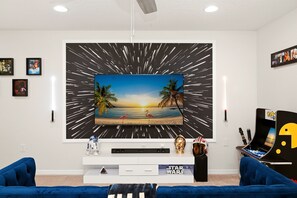 Un salon avec une grande télévision, des objets de collection sur l’univers de Star Wars et un canapé bleu.