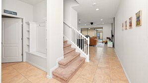 A clean, modern interior with a staircase, white walls, and a tiled floor. - Group Hub Near Disney | 4BR with Pool and BBQ | Windsor of Westside Resort (Four Corners)