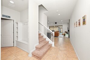 Un intérieur épuré et moderne, avec un escalier, des murs blancs et un sol carrelé.