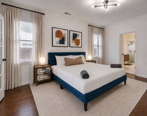 A modern bedroom with a large bed, bedside tables, a rug, and artwork on the wall.