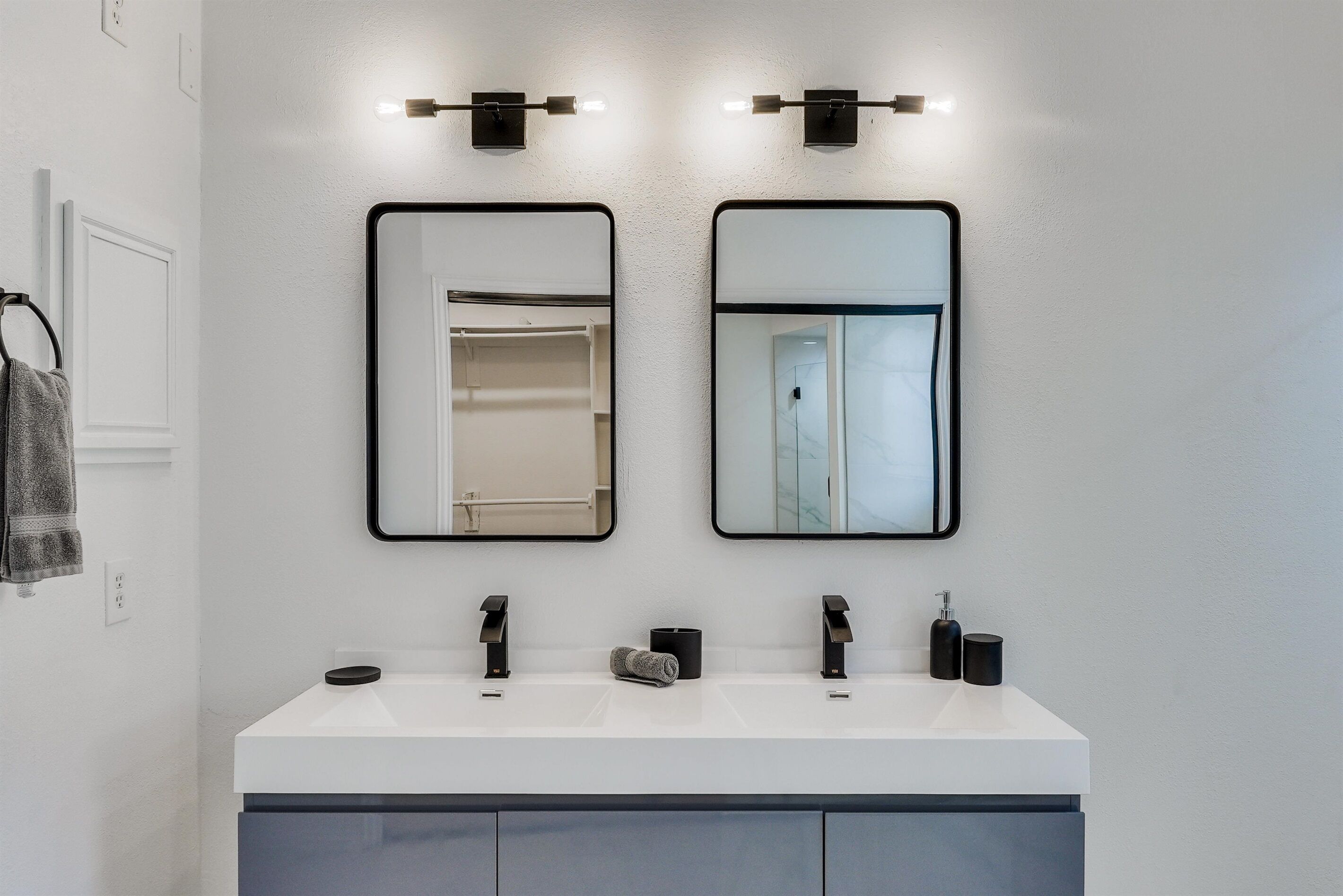A bathroom with two sinks, a towel rack, and a mirror.
