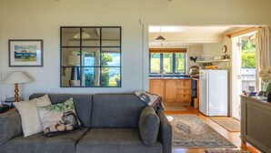 Una sala de estar con un sofá, un comedor con cocina y vistas al exterior.