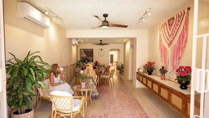 A spacious indoor area with a ceiling fan, potted plants, and a dining area with chairs and tables. - El Canario, double room with garden in Casa Sofia Center (Mérida)