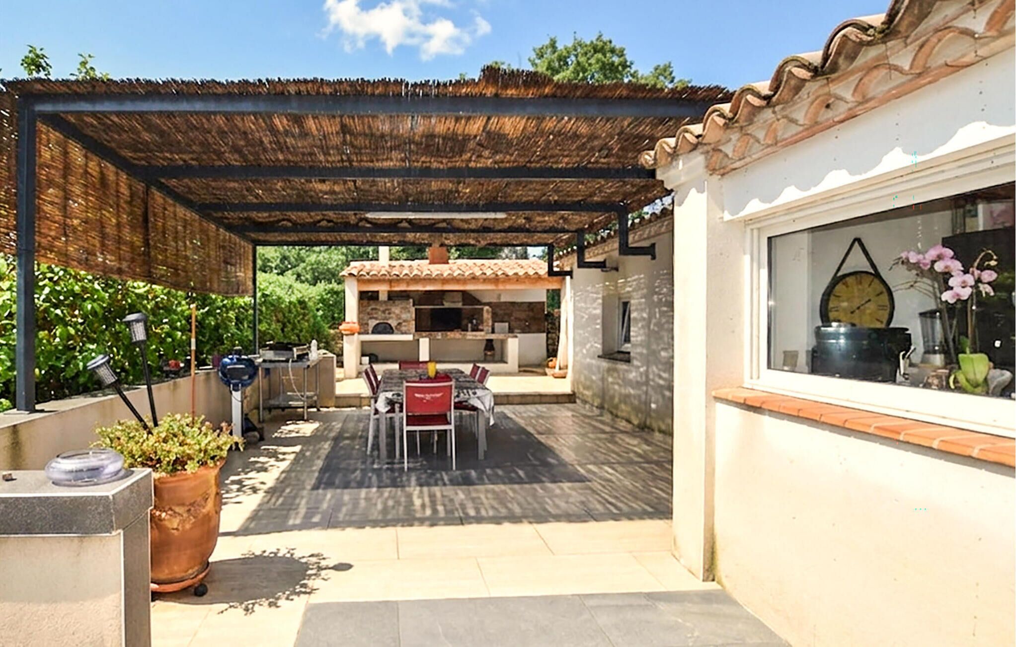 Un patio couvert comprenant une table et des chaises, un barbecue et une plante en pot.