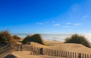Ein sandiger Strand mit Dünen und einem Holzzaun.