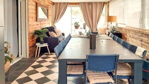 Uma sala de jantar com piso xadrez, uma mesa comprida e cadeiras azuis.