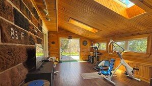 A gym with exercise equipment, wooden walls, and large windows.