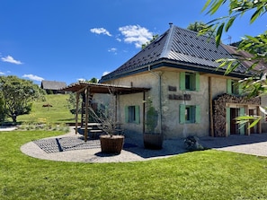 Un bâtiment de style rustique, doté d’un toit en pente, de volets verts et d’un mur en pierre.