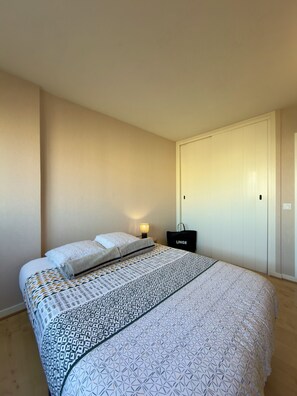 Une chambre à coucher avec un lit, une lampe de chevet, une armoire et un sac étiqueté « LINGE ».