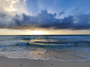 A beach with waves and a cloudy sky.