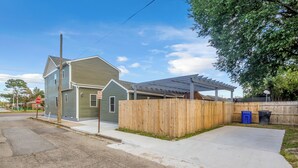 A residential house with a covered patio, a wooden fence, and a stop sign. - Modern Apartment Stay with Fast Wi-Fi and Workspace (Portsmouth)