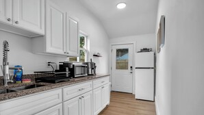 A kitchen with white cabinets, a granite countertop, a coffee maker, and a refrigerator. - Modern Apartment Stay with Fast Wi-Fi and Workspace (Portsmouth)