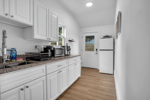 Eine Küche mit weißen Schränken, einer Granit Arbeitsplatte, einer Kaffeemaschine und einem Kühlschrank.