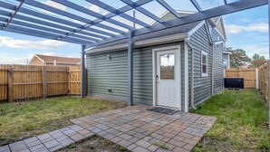 A covered patio area with a wooden fence, a door, and a TV on the wall. - Modern Apartment Stay with Fast Wi-Fi and Workspace (Portsmouth)