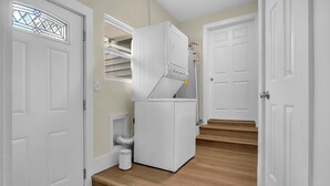 A hallway with a white appliance, a door with a stained glass window, and a staircase. - Modern Apartment Stay with Fast Wi-Fi and Workspace (Portsmouth)