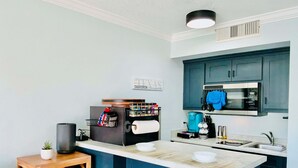 A compact kitchen with a microwave, coffee maker, and a small island with a roll of paper towels. - The Jellyfish Resort-style (Galveston)