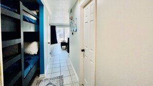 A hallway with a white door, a blue wall, and a patterned rug. - The Jellyfish Resort-style (Galveston)