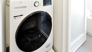 A compact laundry area with a white washing machine, a drying rack, and a basket. - 3 min to Honmachi Stn! Wi-Fi, Great Access to Namba, Umeda & Shinsaibashi (Kitakyuhouji-cho, Osaka City)