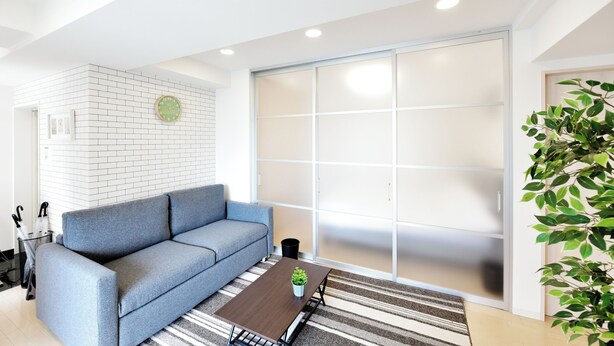 A modern living room with a sofa, a coffee table, and a sliding door. - 3 min to Honmachi Stn! Wi-Fi, Great Access to Namba, Umeda & Shinsaibashi (Kitakyuhouji-cho, Osaka City)