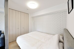 Ein Schlafzimmer mit einem Bett, einem Kleiderschrank, einer Ziegelwand und einer Deckenleuchte.