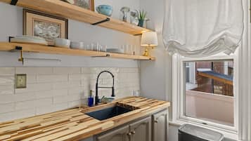 A kitchen with a wooden countertop, a sink, and a window with a view.