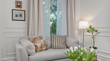 A living room with a sofa, a lamp, a potted plant, and framed pictures on the wall.