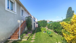 Un immeuble résidentiel doté d’un escalier, d’un jardin bien entretenu et surplombant un ciel bleu dégagé.