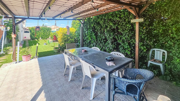 Une terrasse extérieure avec une table et des chaises, entourée de verdure et offrant une vue sur le quartier.