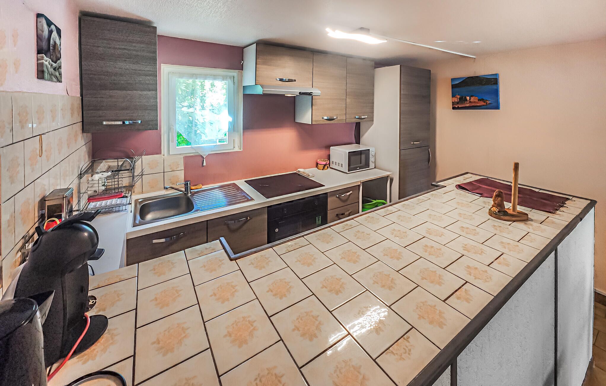 Una cocina con una isla grande, una ventana, armarios y un microondas.