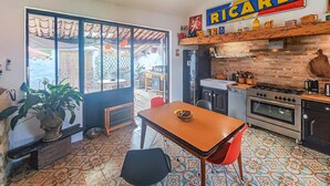 Uma cozinha com área de refeições, geladeira, fogão e um letreiro com a palavra 'RICARD'.