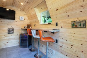 Ein Holzinterieur mit Barbereich, zwei Barhocker, einem Fernseher und einem Schild mit der Aufschrift 'KEEP EXPLORING'.