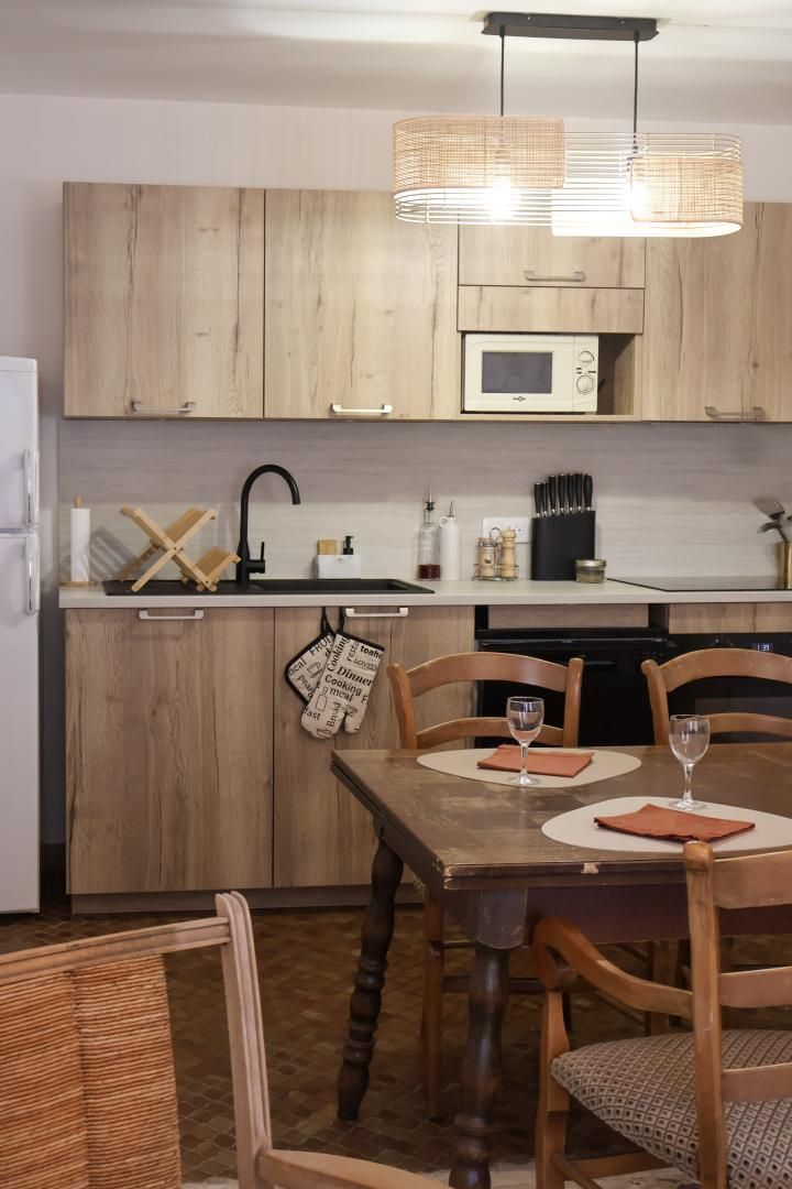 Una cocina moderna con gabinetes de madera, un microondas y un comedor con mesa y sillas.